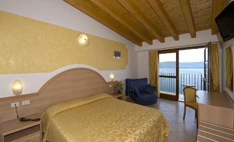 a hotel room with a bed , chairs , and a balcony offering a view of the ocean at All Inclusive Hotel Piccolo Paradiso