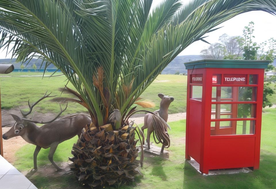a palm tree is next to a red telephone booth with deer standing next to it at Breakers Motel