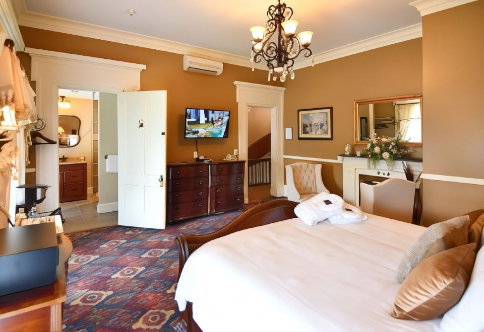 a luxurious hotel room with a king - sized bed , a bathroom , and a tv on the wall at Avon Inn