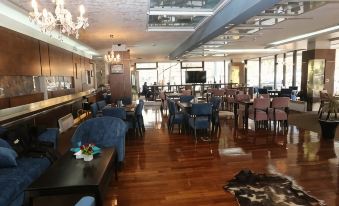 a large dining room with wooden floors , multiple tables and chairs , and a chandelier hanging from the ceiling at Hotel Holiday