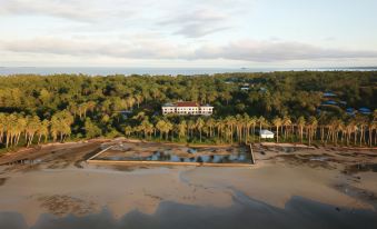 aerial view of a resort surrounded by trees and water , with a large building in the background at Hotel Grand Papua Kaimana