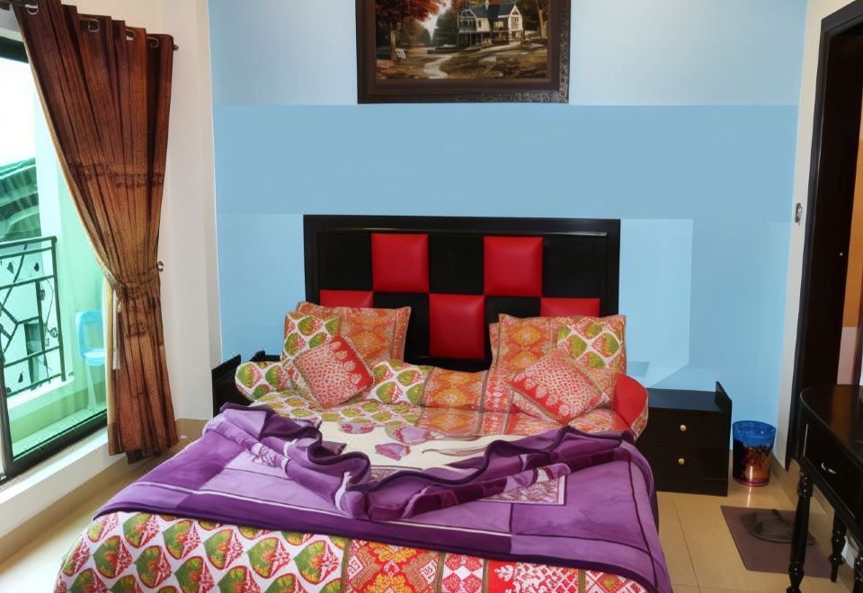 The bedroom features a purple bedspread and red pillows on the headboard at Taj Hotel and Restaurant