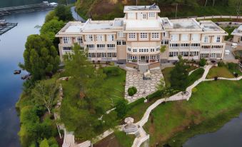 an aerial view of a large , ornate building surrounded by trees and a body of water at Portola Grand Renggali Hotel Takengon