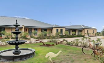 a building with a courtyard and a swan sculpture in front , surrounded by greenery and trees at The Oxley Estate