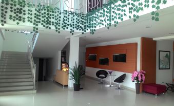 a modern hotel lobby with a staircase leading to the second floor , a reception desk , and several chairs at Hotel Bandara Syariah