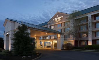 a country inn & suites hotel at dusk , with its lights on and trees in the background at Country Inn & Suites by Radisson, Fredericksburg, VA