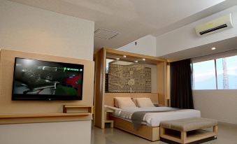 a modern bedroom with a large bed and a flat - screen tv mounted on the wall at Metland Hotel Cirebon by Horison