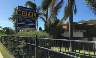 a motel with a large sign in front of it , surrounded by palm trees and grass at Bridge View Motel