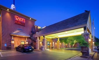 a large , modern hotel building with a red sign above the entrance and a black car parked in front of it at Best Western Plus White Bear Country Inn