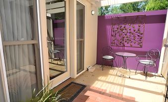 a small , cozy courtyard with a purple wall , a glass door , and a table and chairs at Alexandra Place
