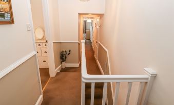 a hallway with a white staircase leading to the second floor , surrounded by beige walls at Avondale