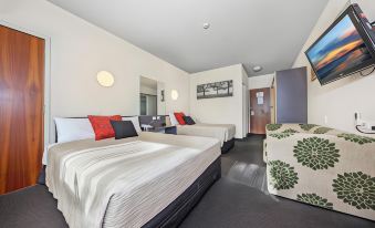 a hotel room with three beds , two of which are twin beds and one is a double bed at Belconnen Way Hotel & Serviced Apartments