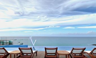 a wooden deck overlooking the ocean , with three lounge chairs placed on a deck overlooking the water at Ocean V Hotel