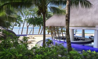 a tropical resort with a swimming pool , umbrellas , and palm trees near the ocean , under a clear blue sky at SO Sofitel Mauritius