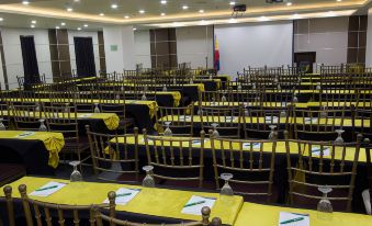 a conference room with rows of yellow tables and chairs , a projector screen , and flags on the table at Eurotel Angeles
