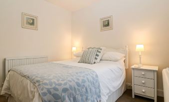 a neatly made bed with blue and white bedding is in a room with two lamps on either side at Avondale