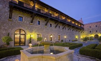 a courtyard with a fountain in the center , surrounded by a brick building with multiple levels of balconies at Parador de Siguenza