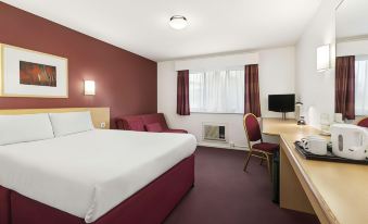 a hotel room with a red and white bed , a desk , a chair , and a television at Days Inn by Wyndham London Stansted Airport