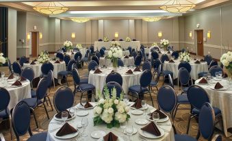 a large banquet hall with multiple round tables set for a formal event , including round tables covered in white tablecloths and surrounded by blue at DoubleTree by Hilton Hotel Oak Ridge-Knoxville