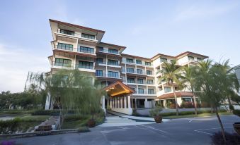 a large , modern apartment building with multiple balconies and trees surrounding the entrance , under a clear blue sky at Parn Dhevi Riverside Resort & Spa