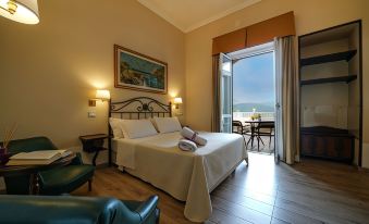 a spacious bedroom with a king - sized bed and a view of the ocean through a sliding glass door at Hotel Scapolatiello