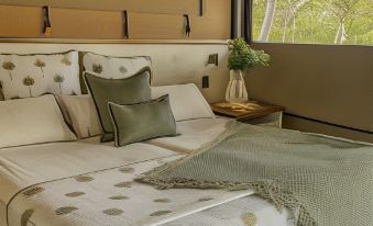 a bed with a white and green patterned blanket is situated in front of a window at Noosa North Shore Retreat