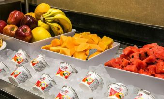 a variety of fruits , including apples and oranges , are displayed in a buffet - style setting on ice at Cambria Hotel Appleton