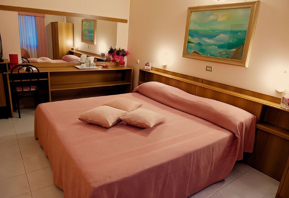 a bed with a pink blanket and two pillows is in a room with a painting on the wall at Hotel Europa