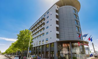 a large , modern building with a circular design is situated on a city street corner at Novotel Tours Centre Gare