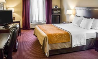 a large bed with an orange blanket is in the middle of a hotel room at Wingate by Wyndham Clearfield