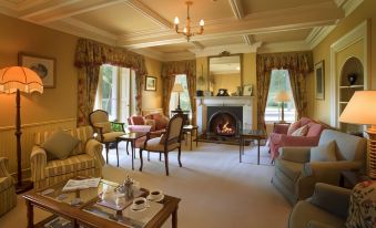 a spacious living room with a fireplace , multiple chairs , and a dining table set for a meal at Lovelady Shield Country House Hotel