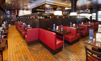 a restaurant with red booths and a brick floor , along with several chairs and tables at Premier Inn Fareham