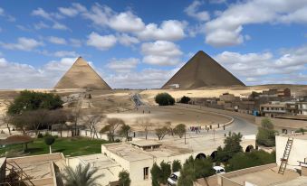 a view of the pyramids of giza , with a group of people walking around the area at Pyramids View Inn