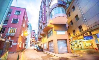 A street in the city is lined with buildings and parked cars on both sides during dusk at Towns Well Motel