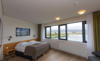 a bedroom with a large window overlooking the ocean , providing a stunning view of the water at Hotel Selfoss