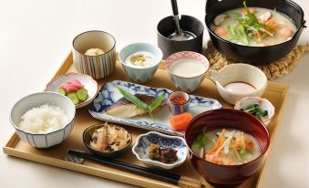 A table is set with plates and bowls filled with small dishes, including sushi on top at Hoshino Resorts KAI Poroto
