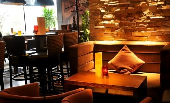 a cozy restaurant with wooden tables and chairs , a stone wall , and a red lamp at Mondo Hotel