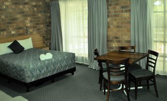 a hotel room with a bed , dining table , and chairs , along with brick walls and a window at Motel Goolwa