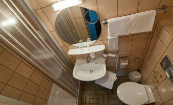 a modern bathroom with a white sink , toilet , and bathtub , as well as a mirror above the sink at Akzent Hotel Schranne