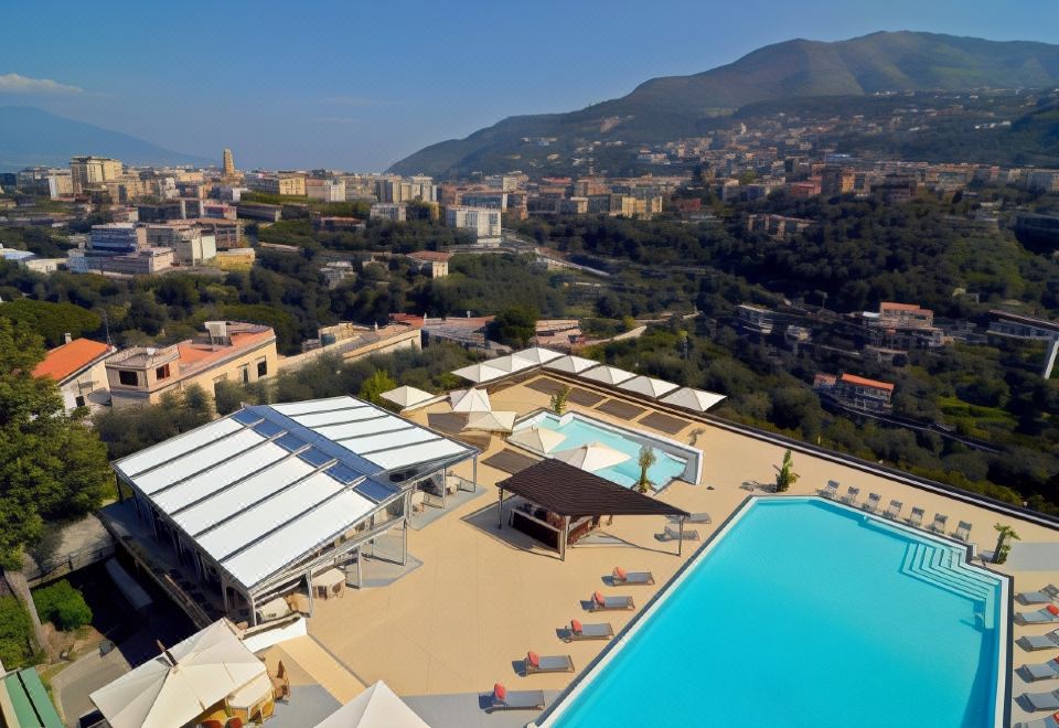 a rooftop pool area with a view of the city , surrounded by lounge chairs and umbrellas at Grand Hotel Moon Valley