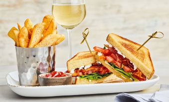 a dining table with a plate of food , a glass of wine , and a knife on the table at Courtyard New Bern