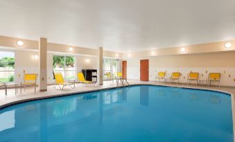 an indoor swimming pool with a large rectangular pool , surrounded by yellow lounge chairs and a patio area at Residence Inn Lansing West