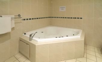 a white bathtub with a silver faucet and handles is placed in a bathroom with tiled walls at Mandarin Motel