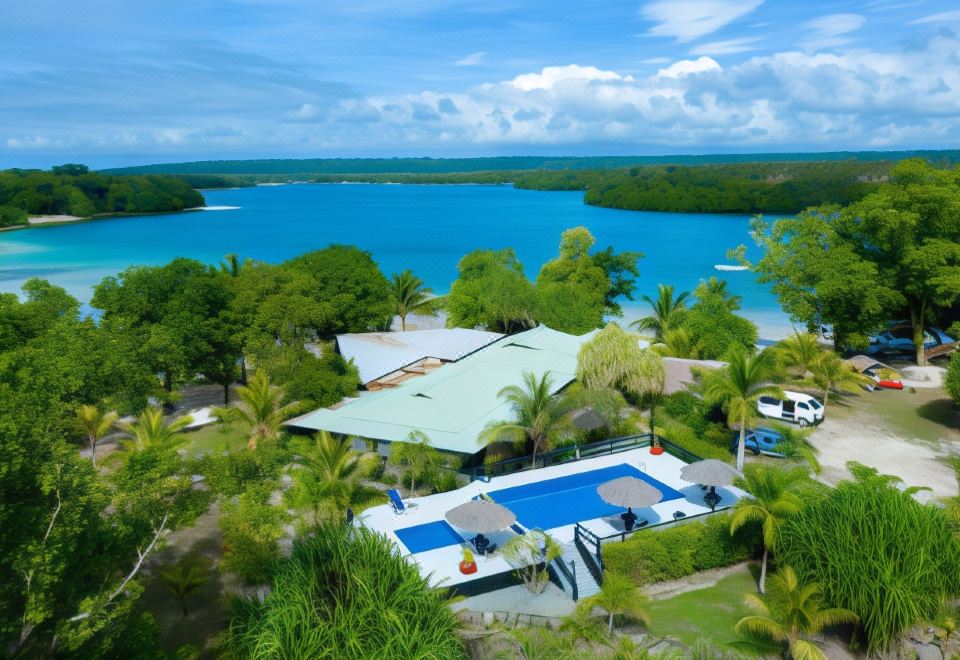 aerial view of a large house surrounded by trees and a lake , with a pool in the background at Turtle Bay Lodge