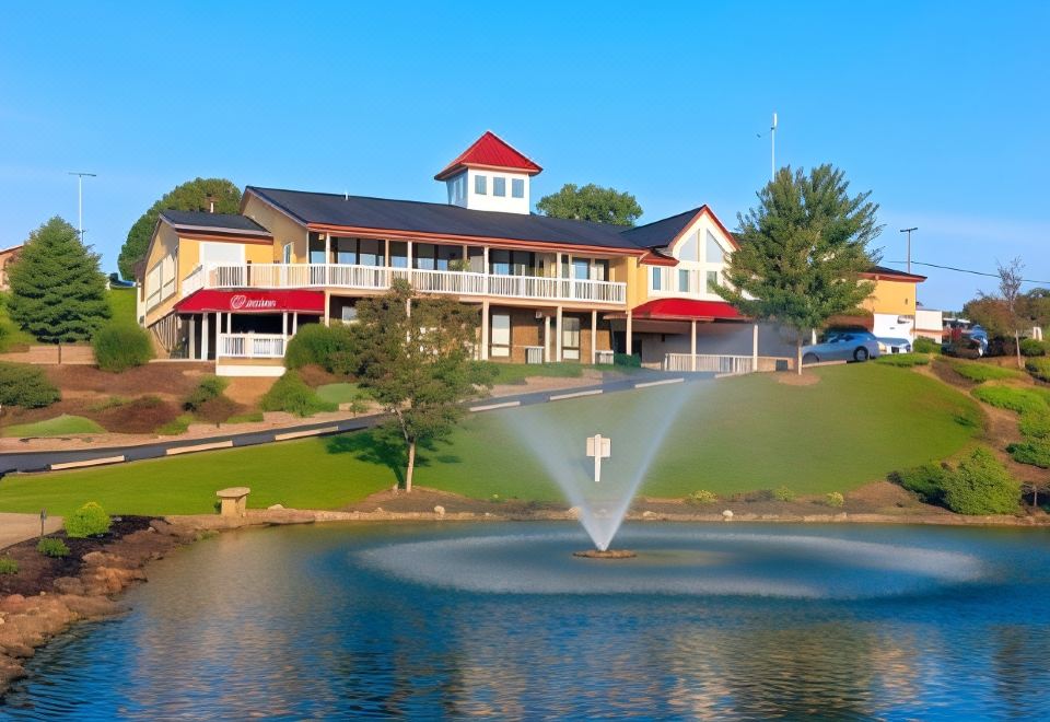 a large house with a fountain in the front yard and a body of water nearby at Berlin Resort