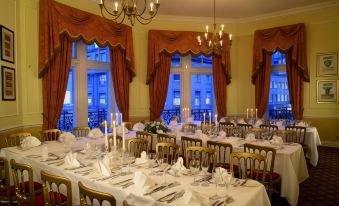 a formal dining room set up for a wedding reception , with multiple tables covered in white tablecloths and set for dinner at Midland Hotel, Bradford