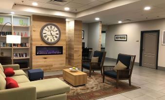 a modern living room with a wooden wall , fireplace , and large clock on the wall at Country Inn & Suites by Radisson, Emporia, VA