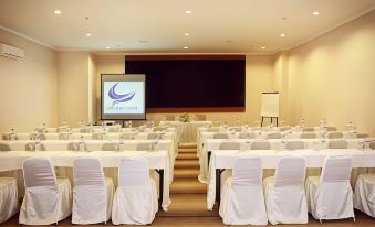 a conference room set up for a meeting , with rows of chairs arranged in a semicircle around a table at Bueno Colombo Hotel Yogyakarta