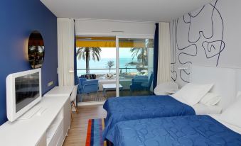 a hotel room with two beds , one on each side of the room , and a balcony overlooking the ocean at Hotel Victoria