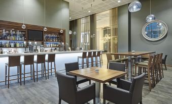 a modern restaurant with wooden tables and chairs , a bar , and a large window at Hilton Garden Inn Sunderland